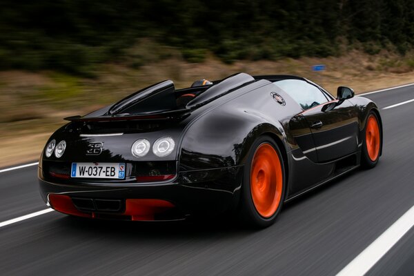 Black Bugatti Veyron corre ad alta velocità lungo la strada