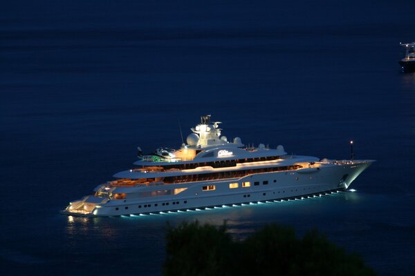 Yate nocturno en medio del mar azul con linternas