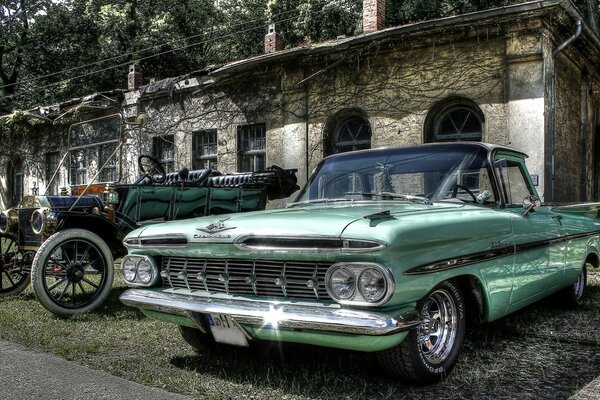 Coches antiguos de pie en la hierba de la casa