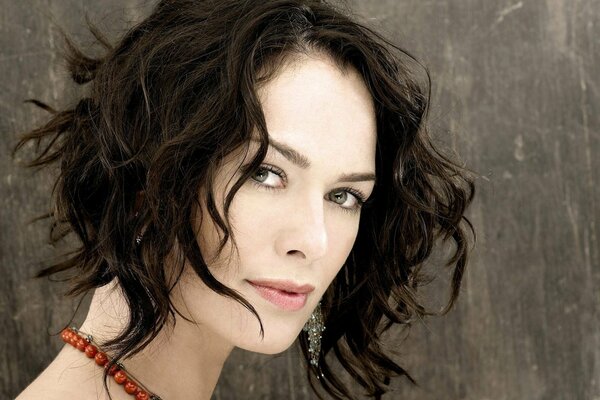 Lena Headey with disheveled hair looks at the camera