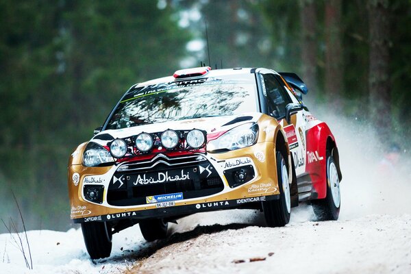 Une voiture de sport se précipite sur une route enneigée au milieu de la forêt