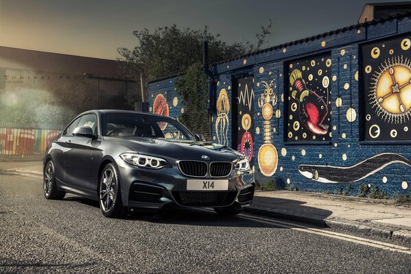 Black BMW on the background of a decorated wall