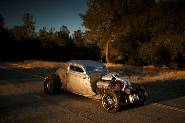 An old car with big wheels is driving on the road