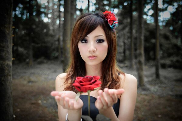 Mujer japonesa en el bosque sostiene una flor roja