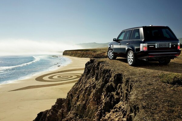 A black car near a cliff on the sea