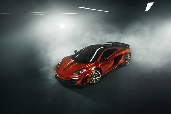 Der orange McLaren MP4-12C steht in einer Rauchwolke