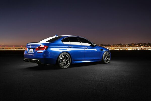 Blue bmw car. Night city on the horizon