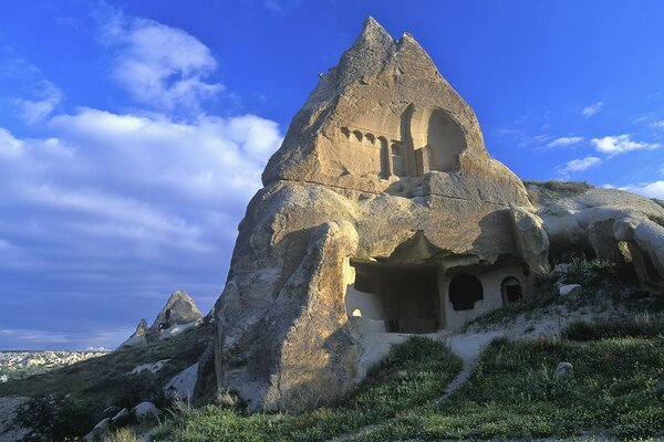 Ein Haus in einem Felsen unter blauem Himmel, das die ganze Kraft der Berge widerspiegelt