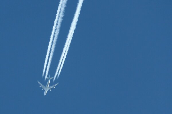 Самолет летиит в синем небе оставляя белый след