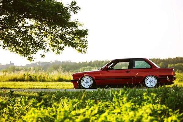 A red car is driving through the countryside