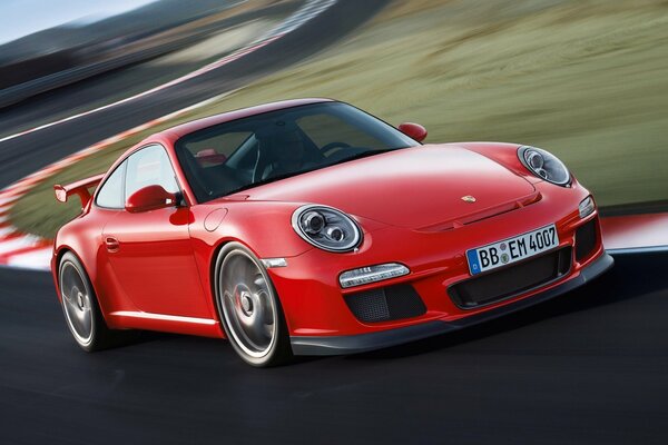 The car is a red porshe racing on the highway