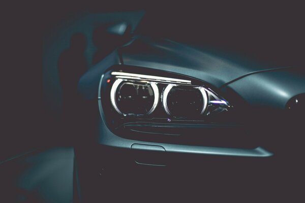 Glowing headlights of a black BMW car