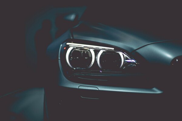 Светящиеся фары черного автомобиля BMW