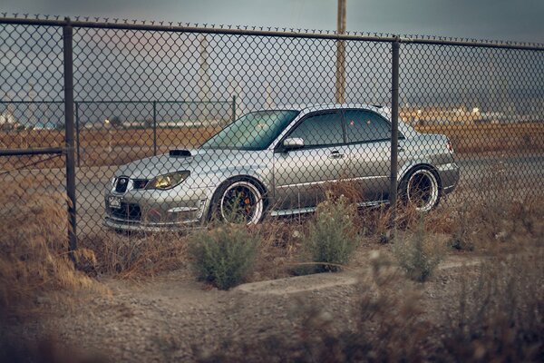 Beautiful car behind an iron fence in the parking lot