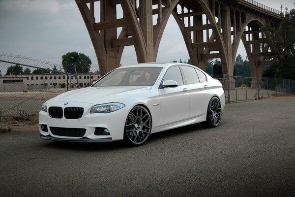 Chic white BMW 550 ai under the bridge