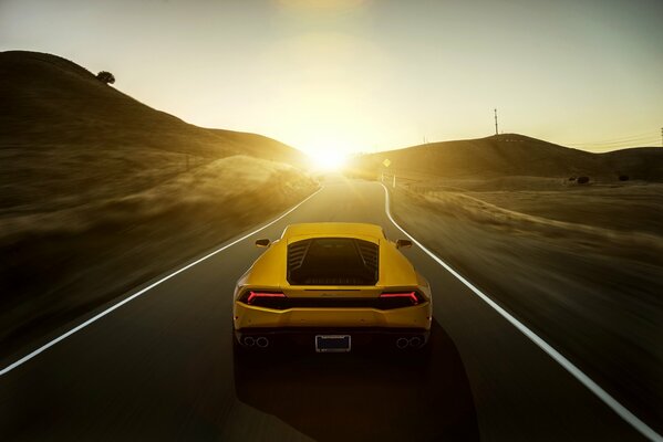 Rear view of a yellow lamborghini car at sunset