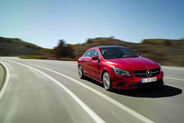 Une Mercedes Benz rouge vole sur une route de campagne