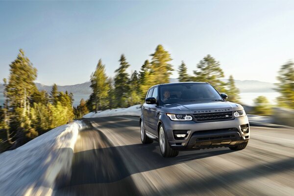 Range rover in winter , range rover on a winter road outside the city , range rover in motion on a highway outside the city , range rover in motion against the background of mountains and forests