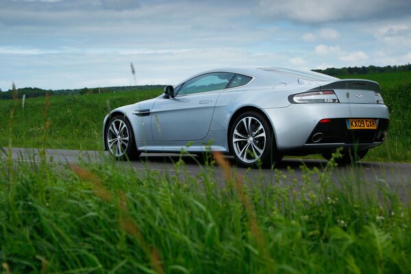 Aston Martin sulla strada su uno sfondo di erba