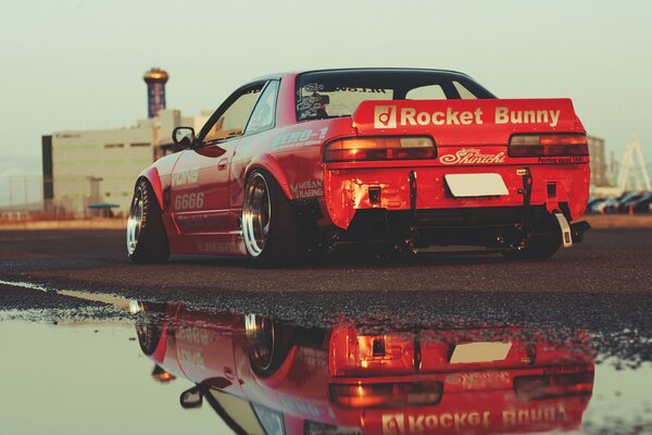 Red Nissan gtr with reflection in a puddle