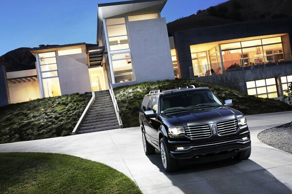 Un SUV noir se tient devant une grande maison de verre