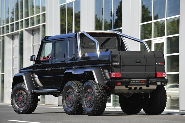 Czarny mercedes-benz Brabus G63 zatrzymał się przed salonem samochodowym