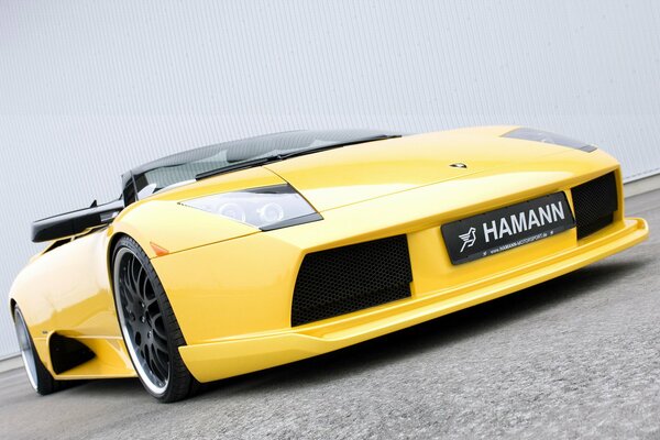 Bella supercar Lamborghini gialla inclinata contro un muro bianco