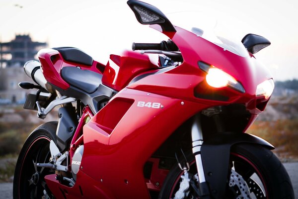 Red Ducati motorbike with headlights on