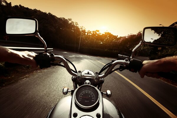 Motociclista guida sulla strada per il tramonto