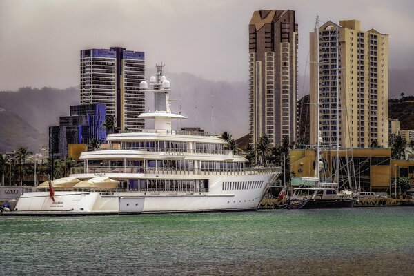 A large white yacht on the pier against the background of a large pride