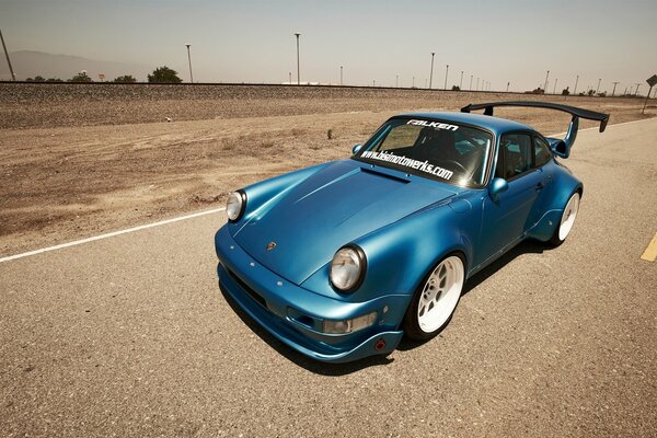 Porsche 911 azul en la pista del desierto