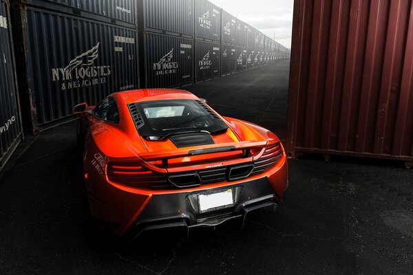 Orange mclaren mp4 -vx drives between shipping containers