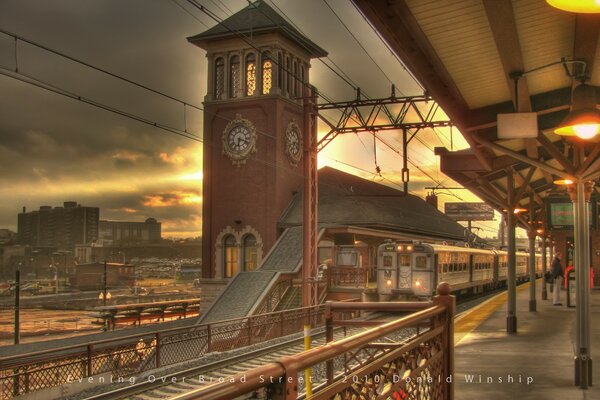 Bahnhof mit Uhr und ankommendem Zug