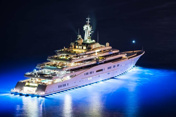 A cool illuminated yacht sails on the water at night