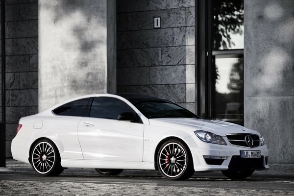 Mercedes C63 AMG blanc sur fond de bâtiment