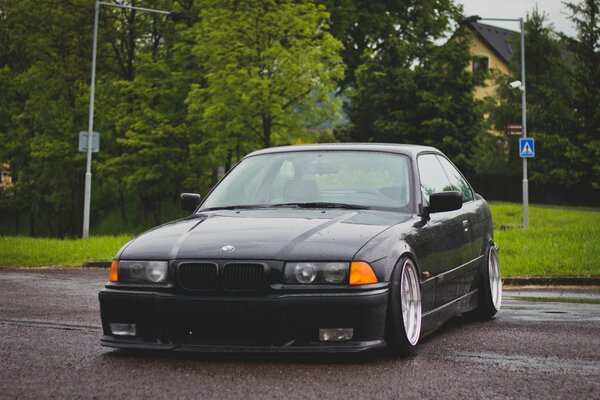 Tuneado negro BMW E 36 en el fondo de los árboles verdes