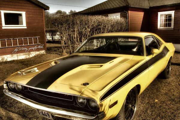 Coche amarillo Mustang en el patio de las casas de madera