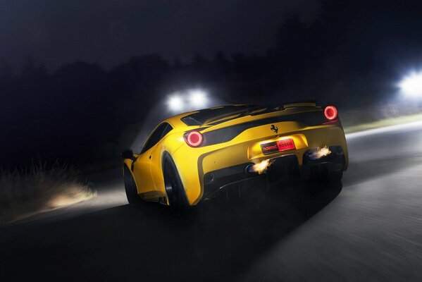 Ferrari amarillo vista trasera monta en la carretera nocturna