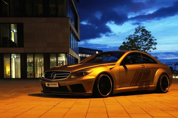 A beautiful silver Mercedes is parked in the evening near the house