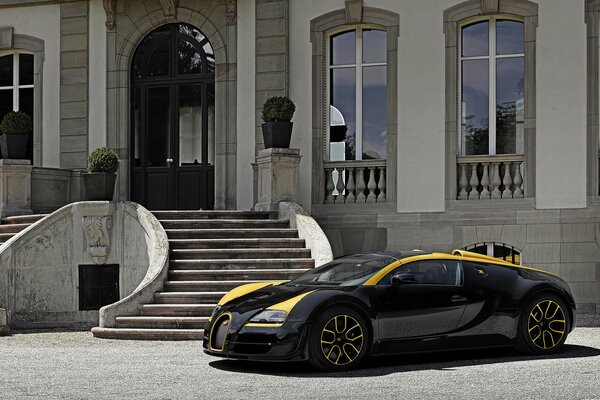 Ein cooler schwarzer Bugatti mit gelben Streifen hielt an einem luxuriösen weißen Herrenhaus an