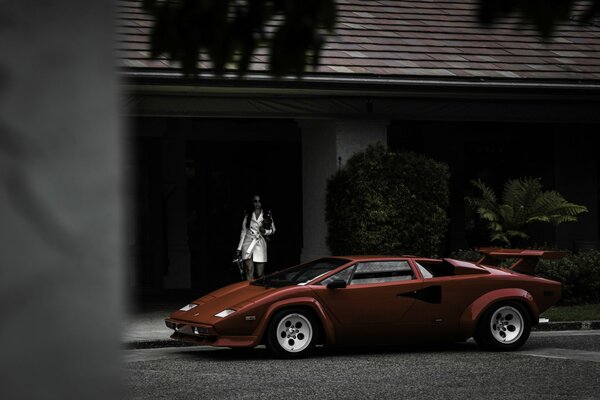 The girl left the house and approaches the red Lamborghini
