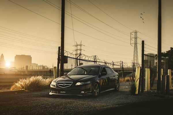 Black acura in the rays of the sun in an industrial area