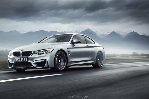 Une bmw argentée dans le brouillard se précipite sur la route