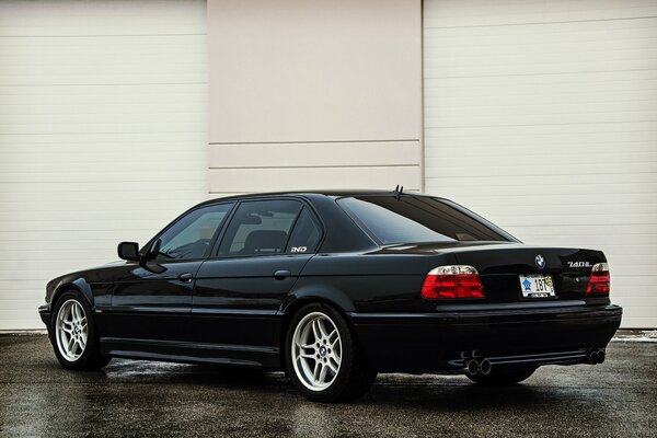 BMW e380 740il black rear view on beige wall background