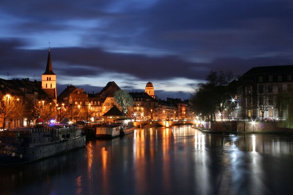 The lights of the city are reflected in the river