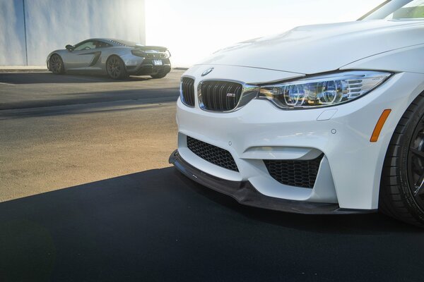 White in front of a BMW on the background of a McLaren