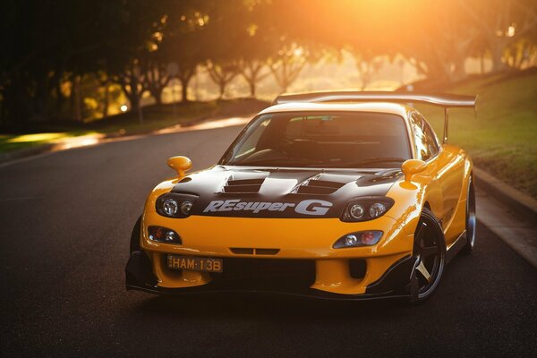 Mazda jaune sur la route au soleil couchant