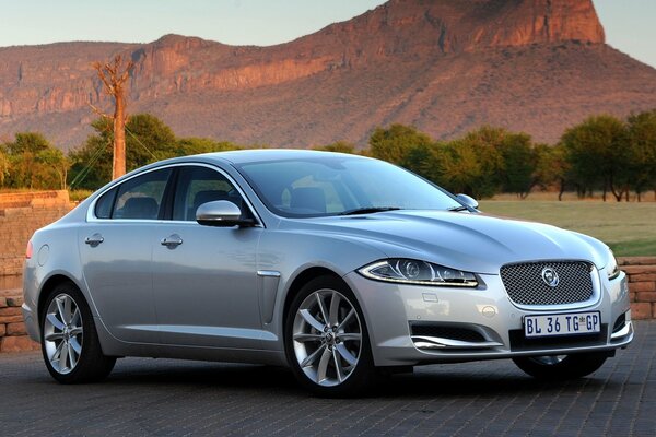 Berline argent Jaguar XF sur fond de montagnes