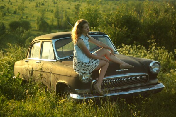 Sur la voiture Volga de l époque de l URSS, une fille est assise dans la bonne humeur