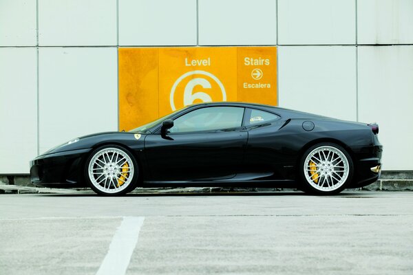 Ferari black against a white wall in the parking lot